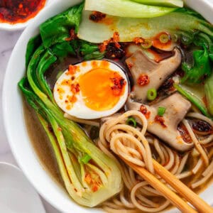 Chopsticks in a bowl of Bokchoy Soup with mushrooms, soft boiled egg, noodles and chilli