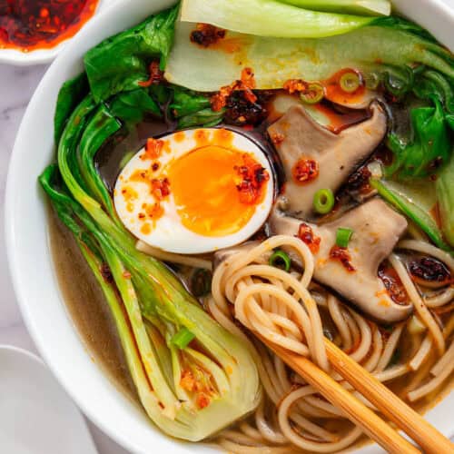 Chopsticks in a bowl of Bokchoy Soup with mushrooms, soft boiled egg, noodles and chilli