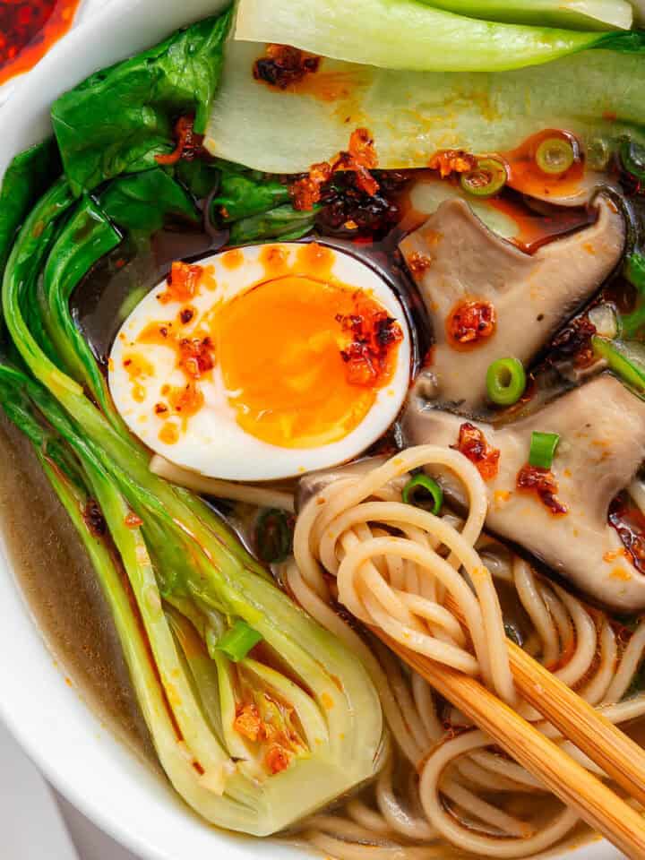 Chopsticks in a bowl of Bokchoy Soup with mushrooms, soft boiled egg, noodles and chilli