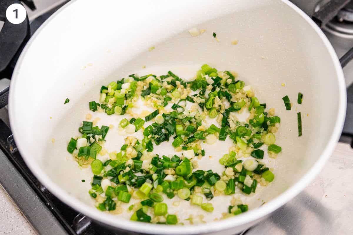 Garlic, ginger and green onions being sautéed with oil in a pot