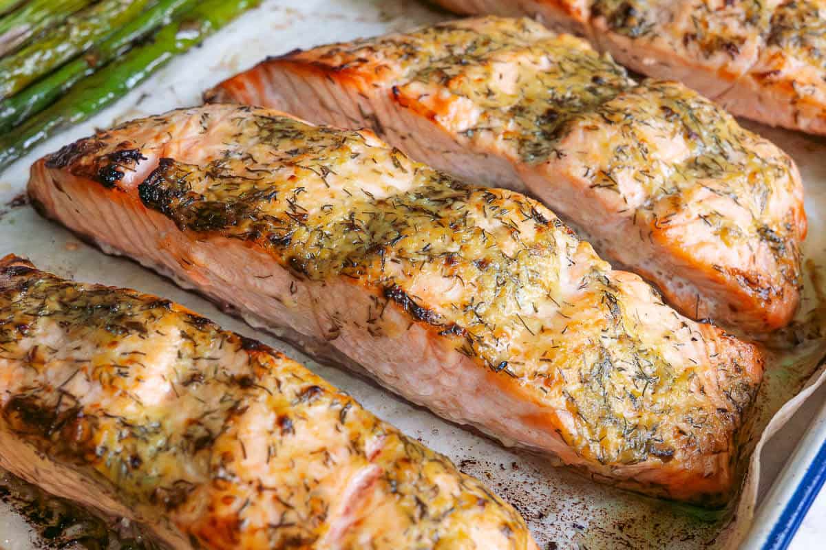 Baked dijon salmon fillets with asparagus on an oven tray