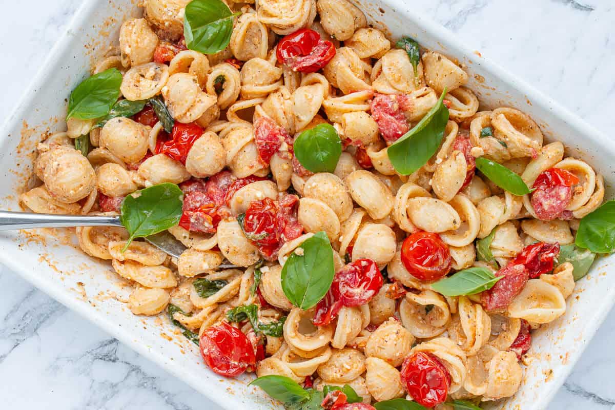 Baked feta pasta in an oven dish with silver spoon