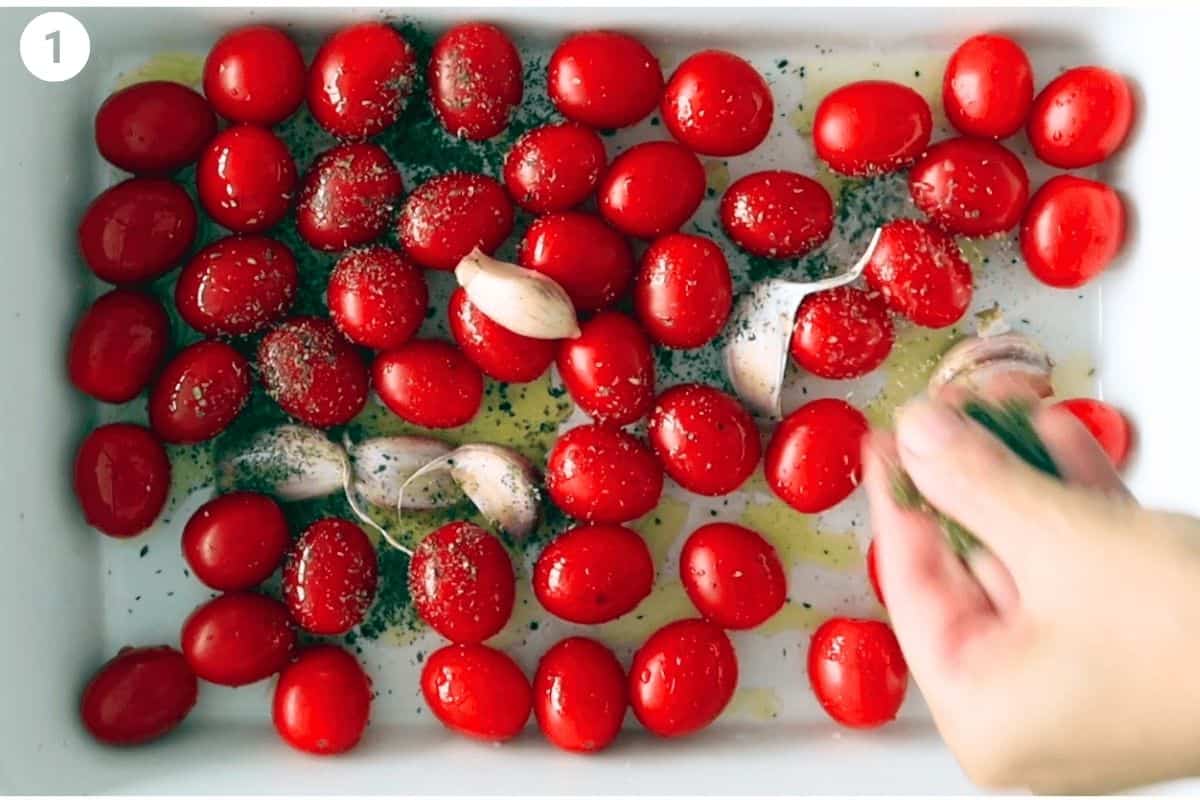 Cherry tomatoes and garlic cloves seasoned with oregano and olive oil in an oven dish