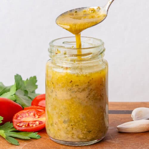Teaspoon full of Italian Dressing being poured into a small glass jar