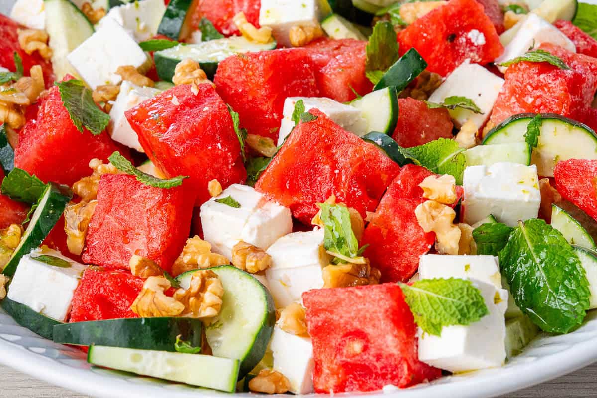 Close up of Watermelon Feta Salad in a large bowl with fresh mint and walnuts