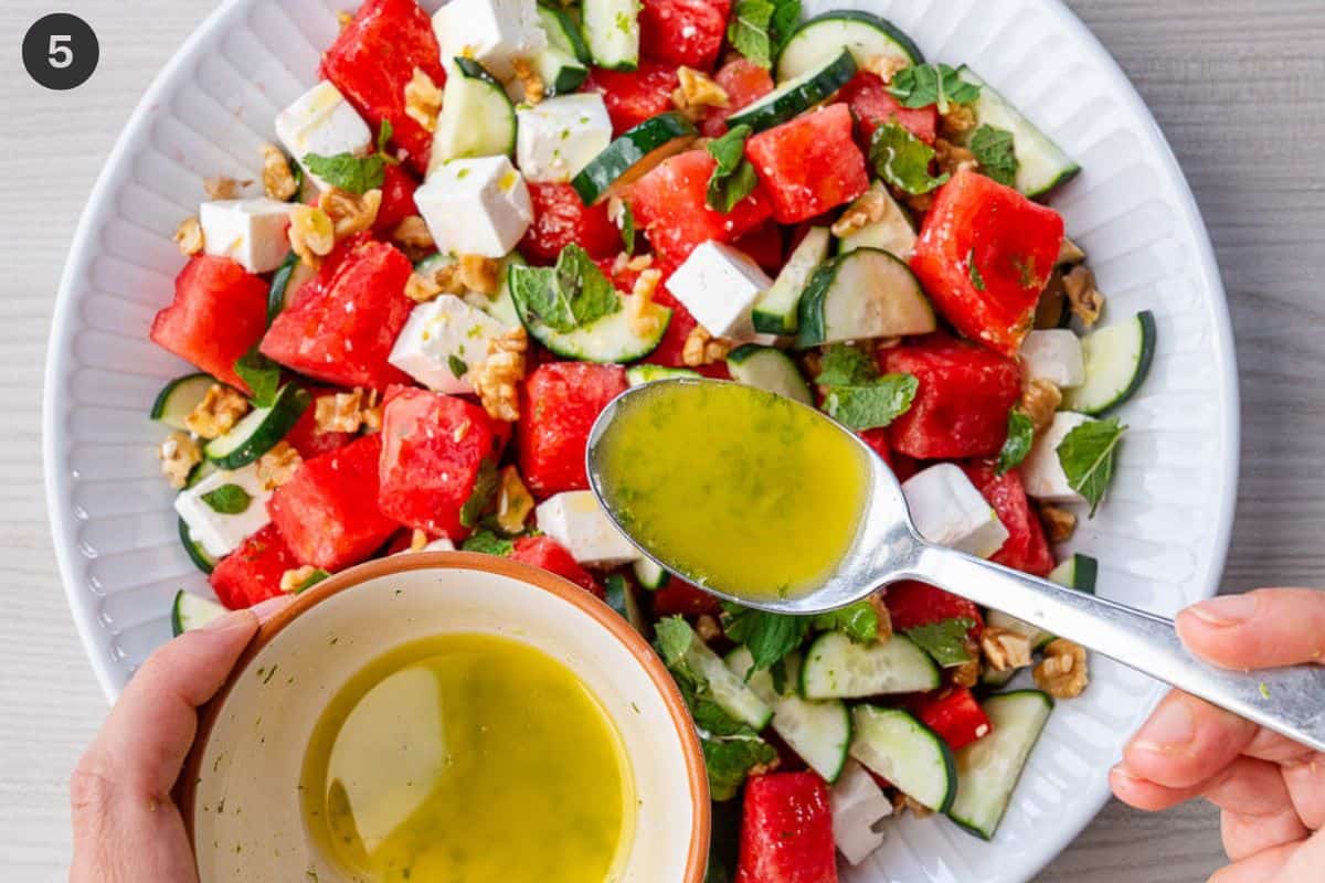 Dressing being poured over the salad with a tablespoon