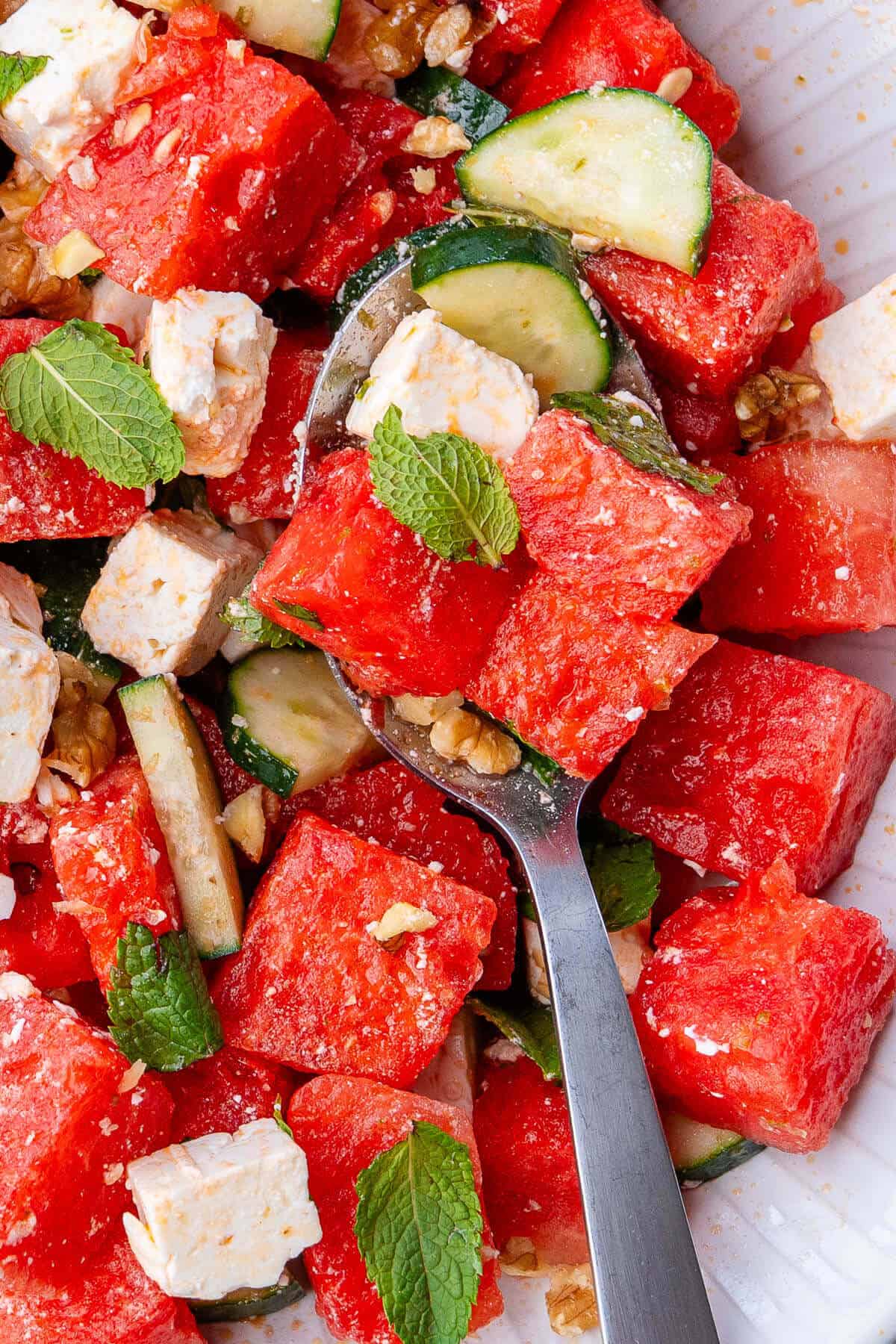 Close up of spoon in a large bowl of watermelon salad