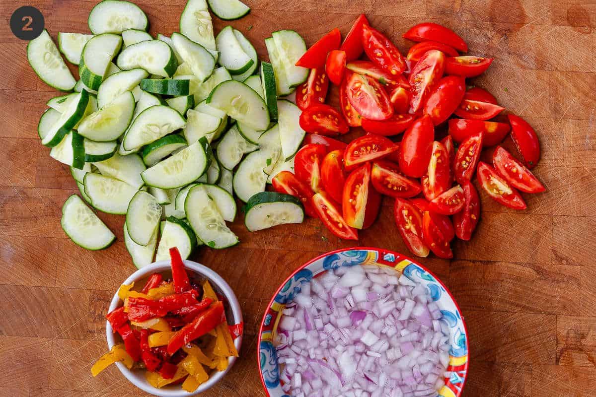 Veggies prepared on a cutting board and onions diced and soaked in water