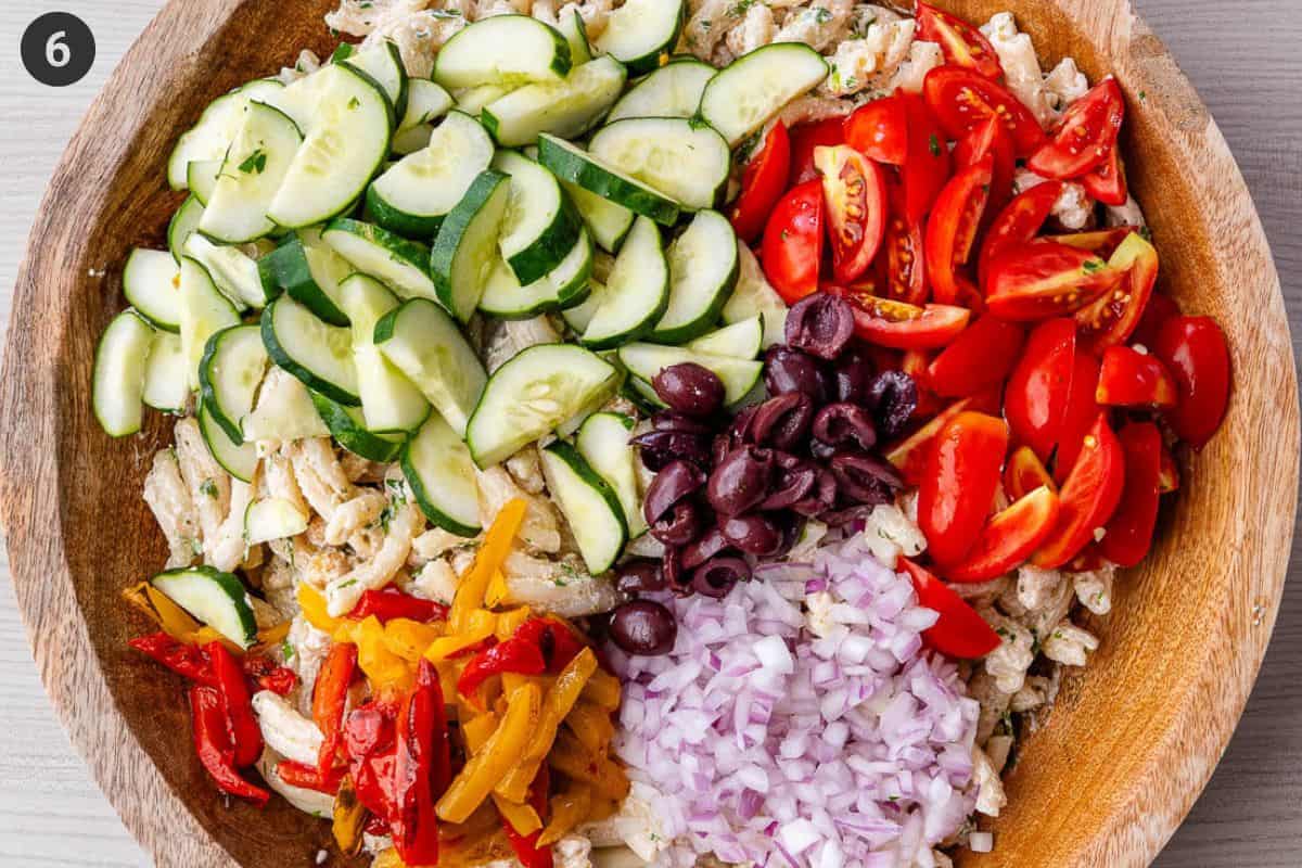 Veggies added to pasta salad bowl then tossed