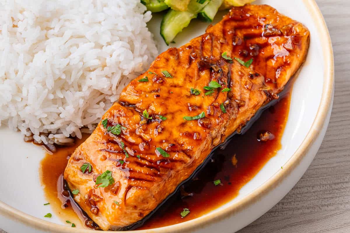 Honey garlic salmon served in a bowl with jasmine rice and avocado cucumber salad