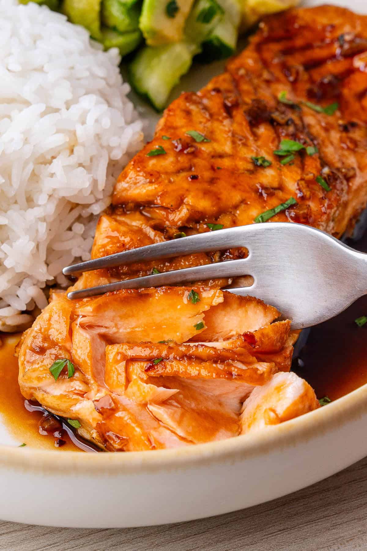 Fork breaking through the salmon to show how tender and flakey it is
