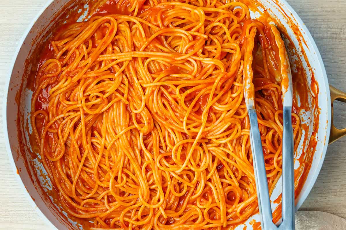 Large pan of spaghetti al pomodoro with tongs