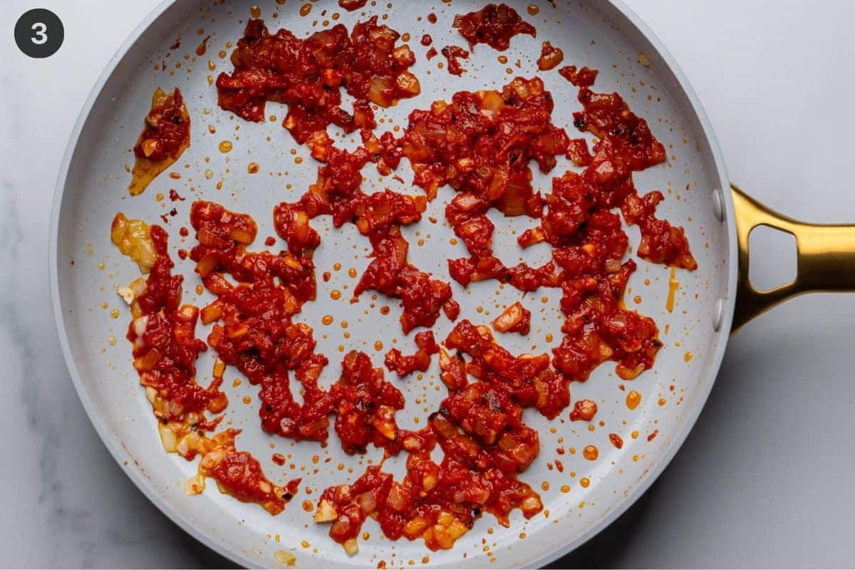Tomato paste being cooked down with onions and chili flakes
