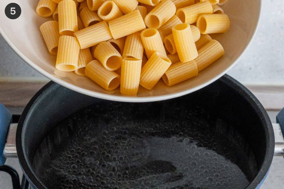 Rigatoni pasta being added to a pot of boiling water