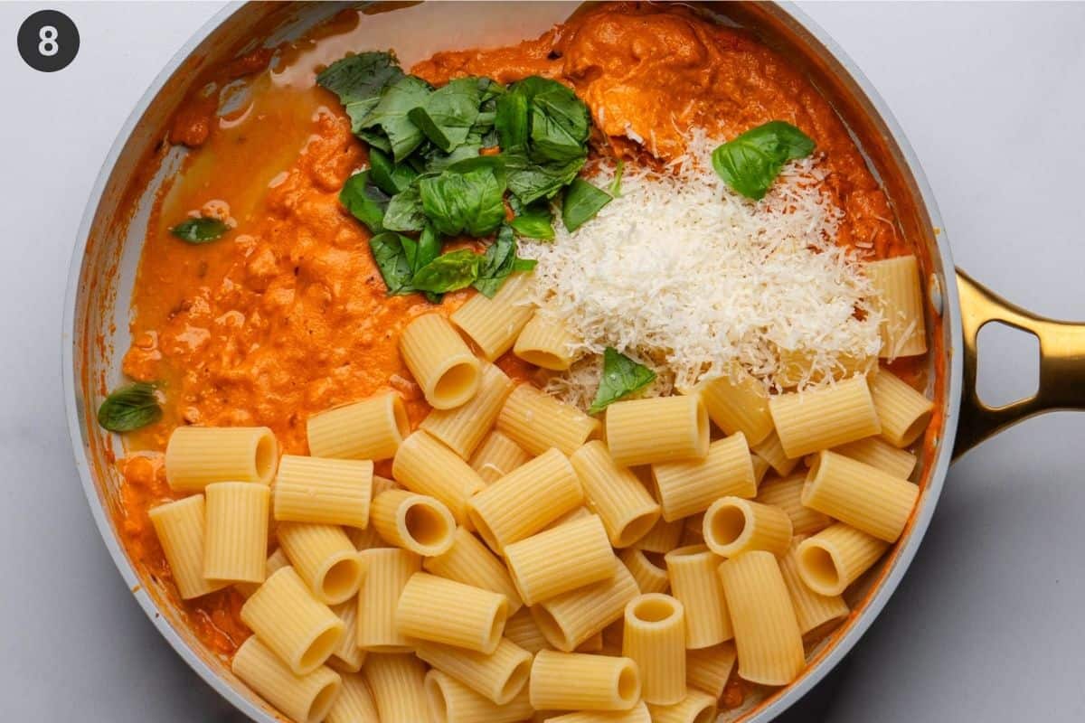 Final step of adding cooked pasta, parmesan cheese, pasta water and torn basil leave before being tossed together