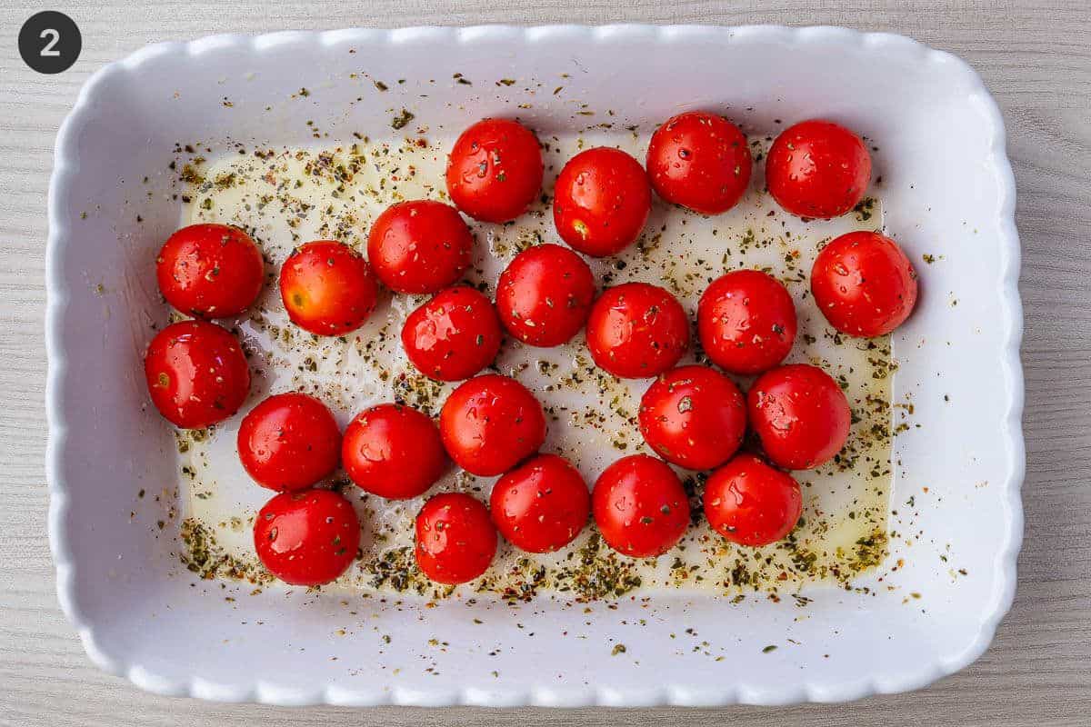 Cherry tomatoes seasoned with oregano, olive and red pepper flakes in an oven dish