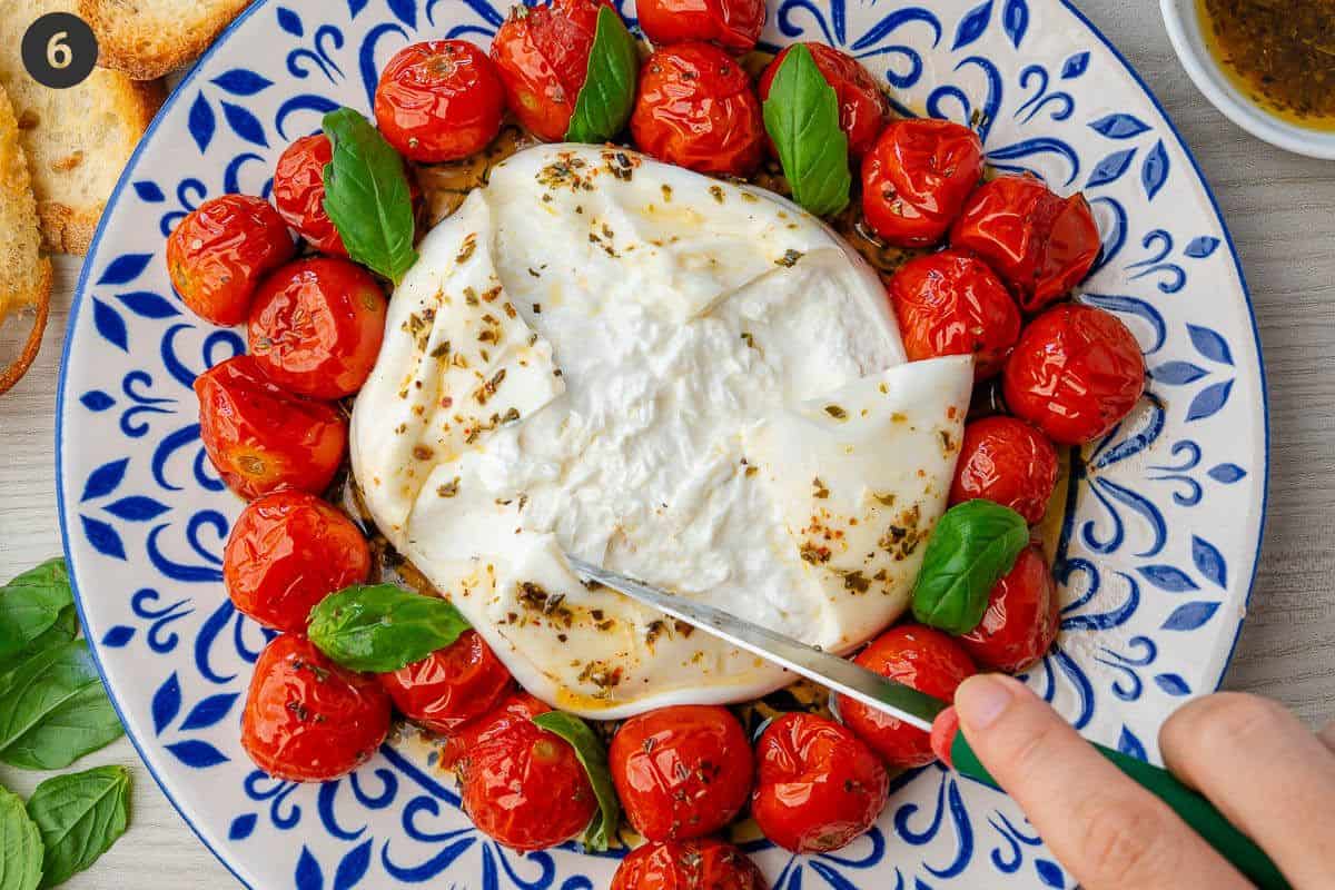 Final burrata appetizer ready to serve with knife cutting through the burrata