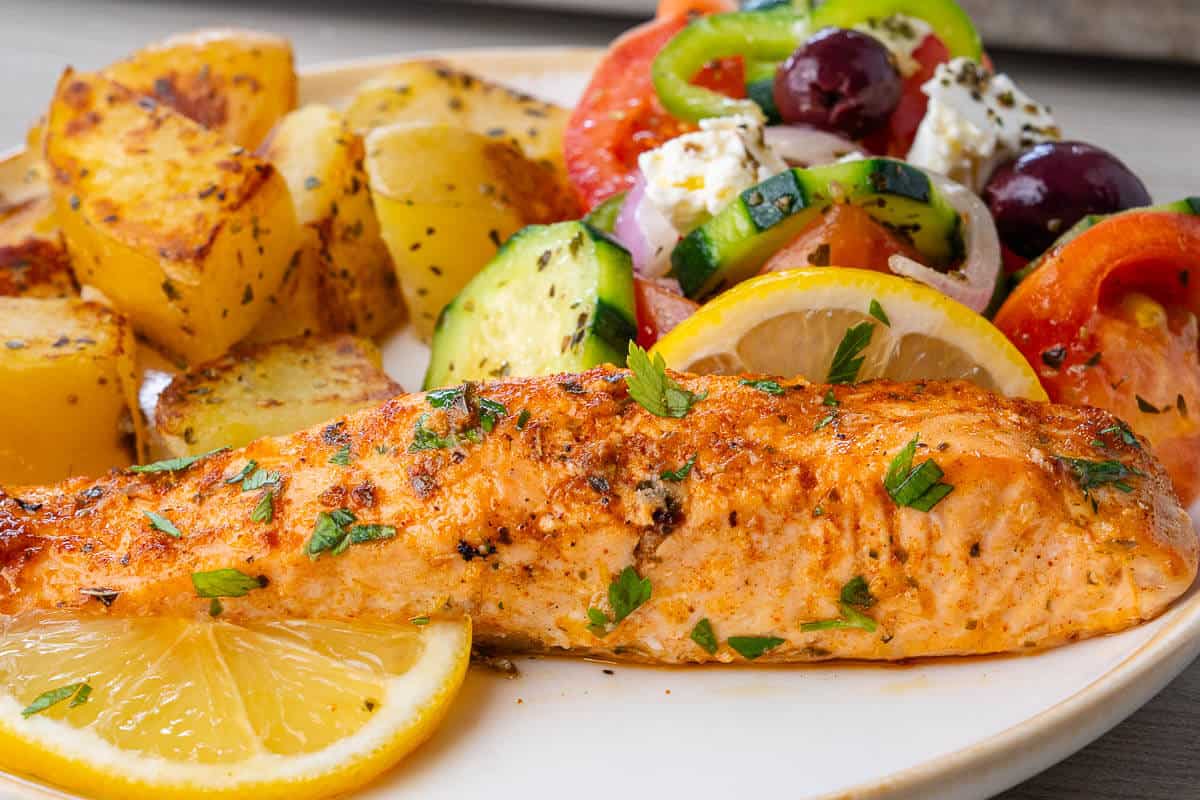 Greek salad served alongside lemon garlic salmon and roasted potatoes