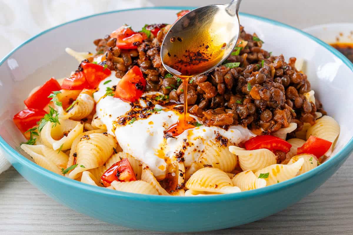 Spoon of aleppo pepper being drizzled over Turkish Pasta