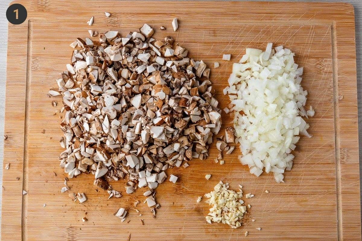 Mushrooms, onions and garlic chopped on a cutting board