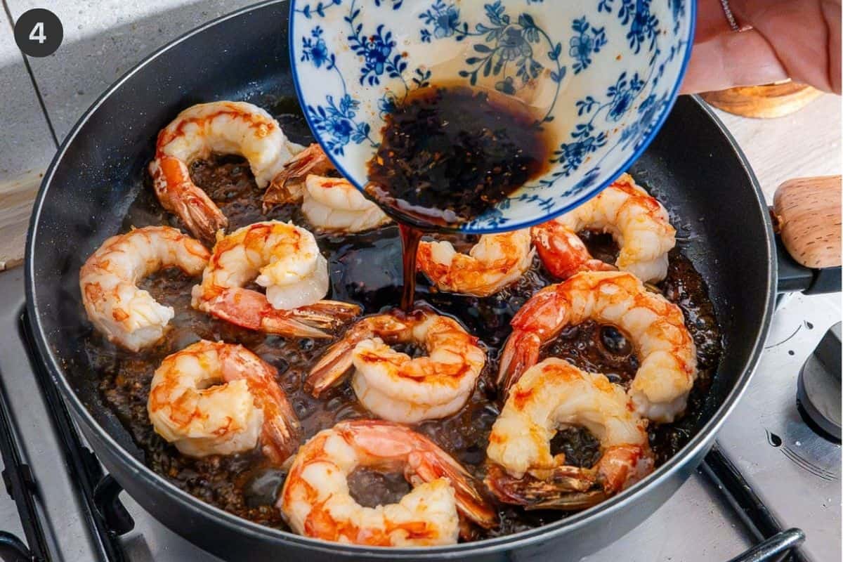 Honey garlic sauce being poured over the shrimp in a pan
