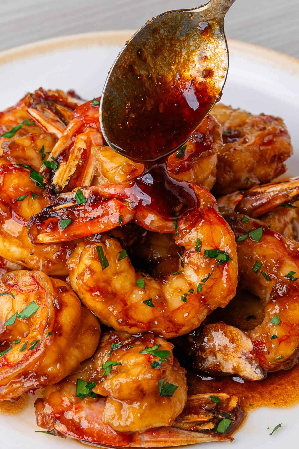 Honey garlic glaze being poured over shrimp with a spoon