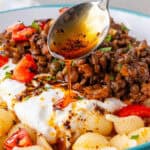 Spoon of aleppo pepper drizzled over Turkish Pasta