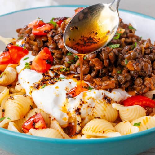Spoon of aleppo pepper drizzled over a bowl of Turkish Pasta