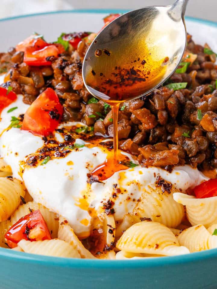 Spoon of aleppo pepper drizzled over a bowl of Turkish Pasta